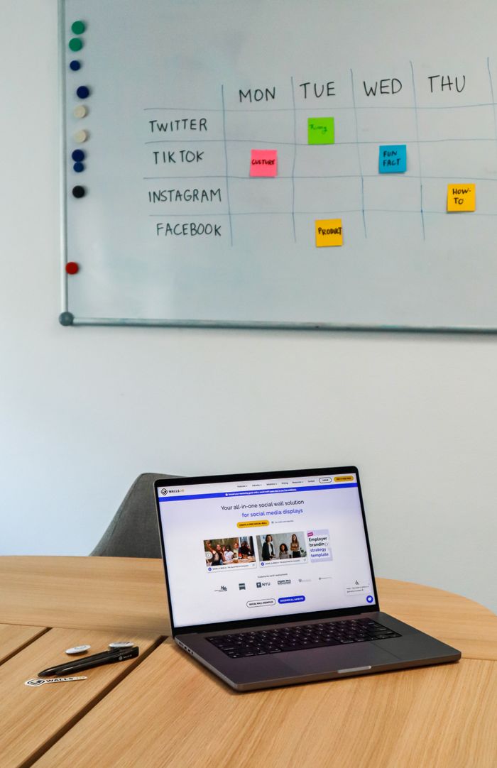 about-04 A contemporary office arrangement with a laptop and a whiteboard schedule for social media platforms.